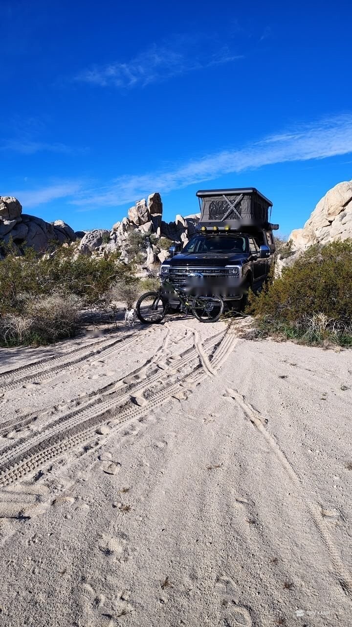 Pickup med kabin i sanddyne under blå himmel