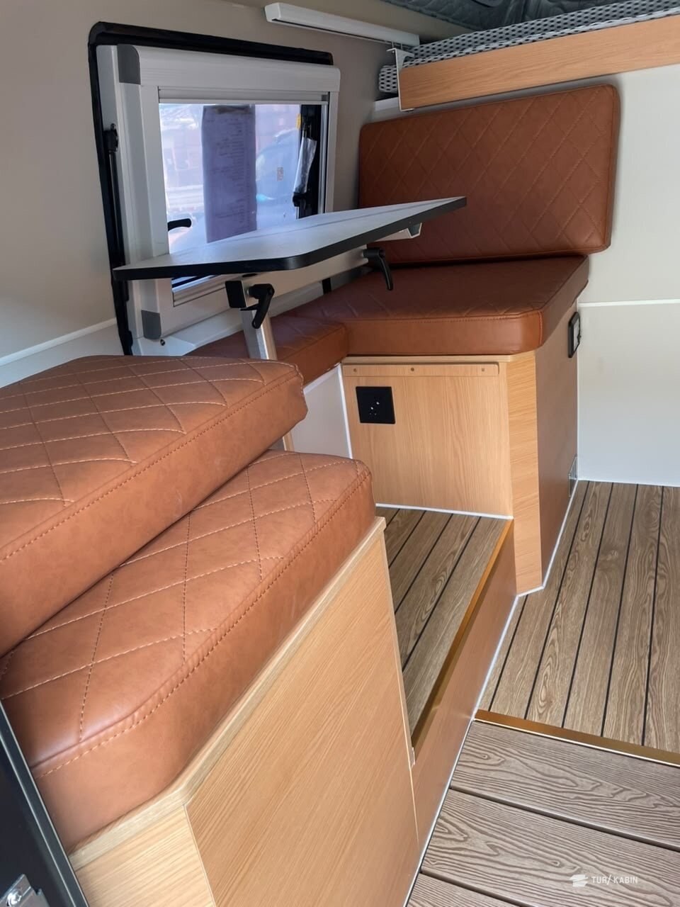 Innvendig sitteplass med bord slått ned og vindu